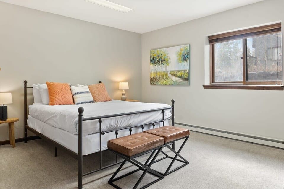 The second basement bedroom boasts a queen-size bed, a dresser, a closet, and a bench at the foot of the bed.