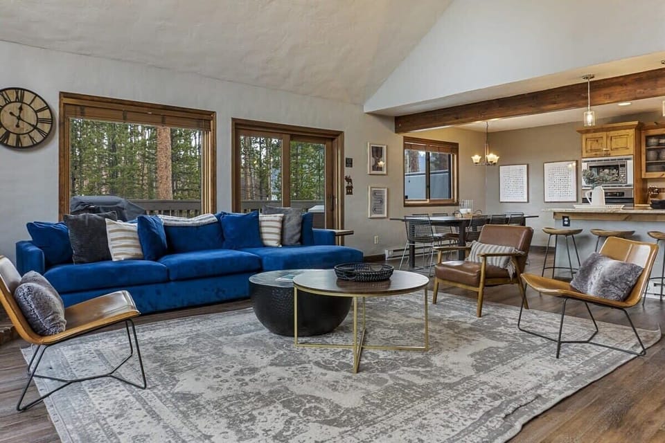The cozy living room features an eye-catching sectional sofa, three sitting chairs, a TV, and a charming wood-burning fireplace on a red brick hearth.