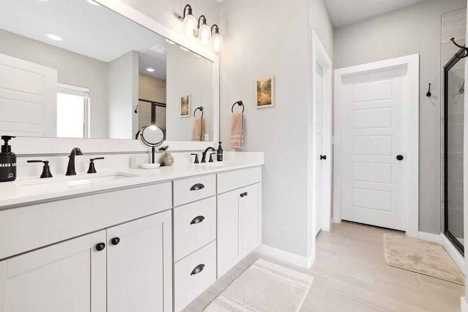 This en suite bath has two sinks, a glass shower, a free-standing tub and lots of storage.