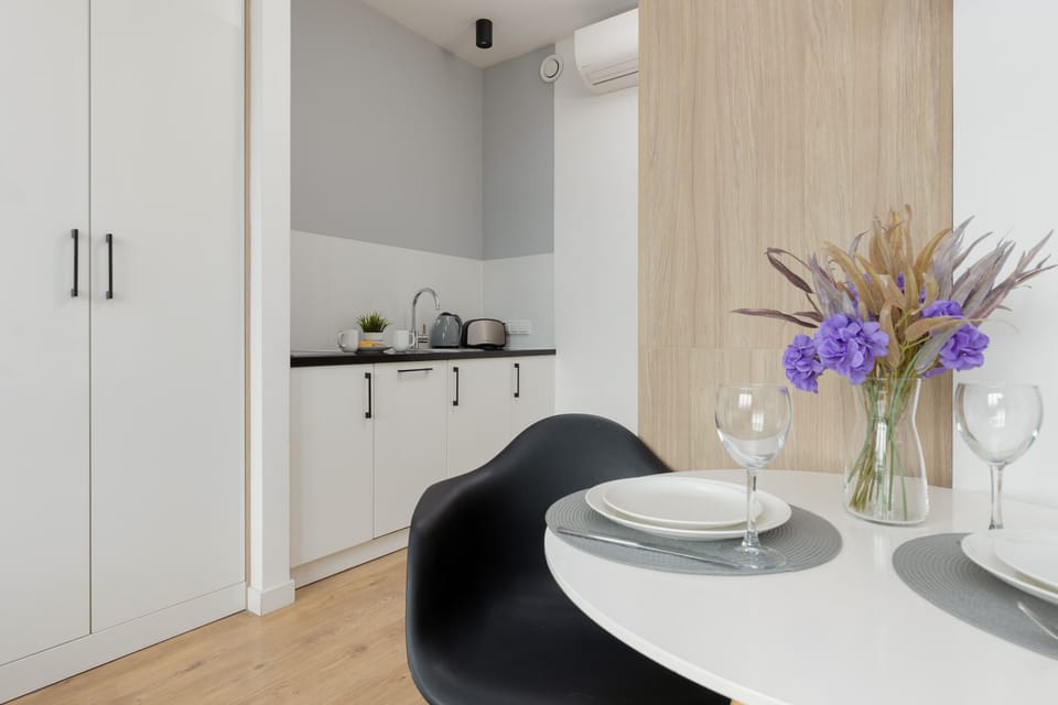 Kitchenette with electric cooktop, electric kettle, microwave, dishwasher, refrigerator with freezer, toaster, kitchen utensils and tableware, washing machine and table with chairs.