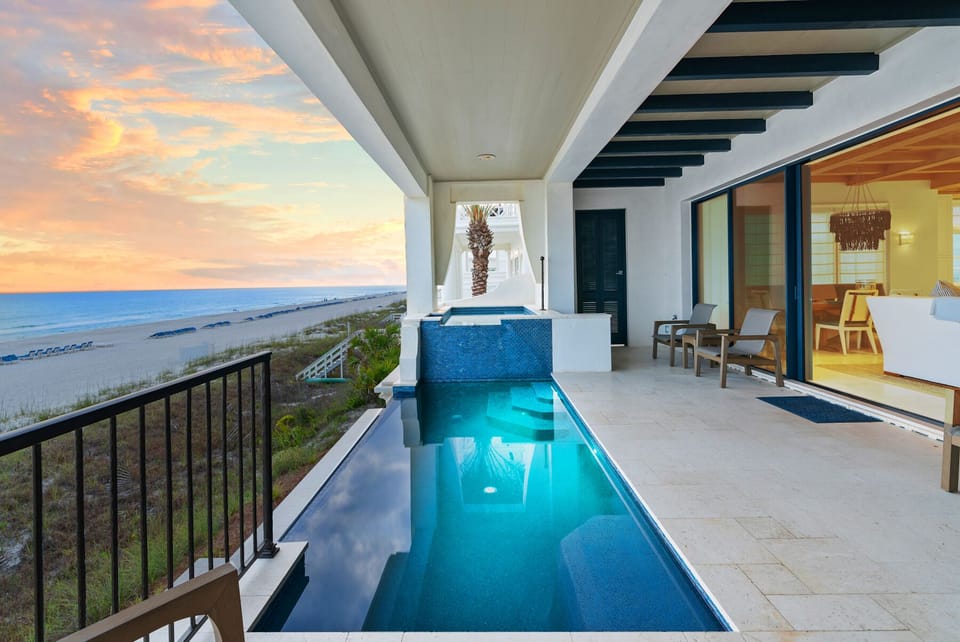 Spectacular beachfront terrace featuring a stunning infinity pool overlooking pristine sandy shores and dramatic sunset skies.