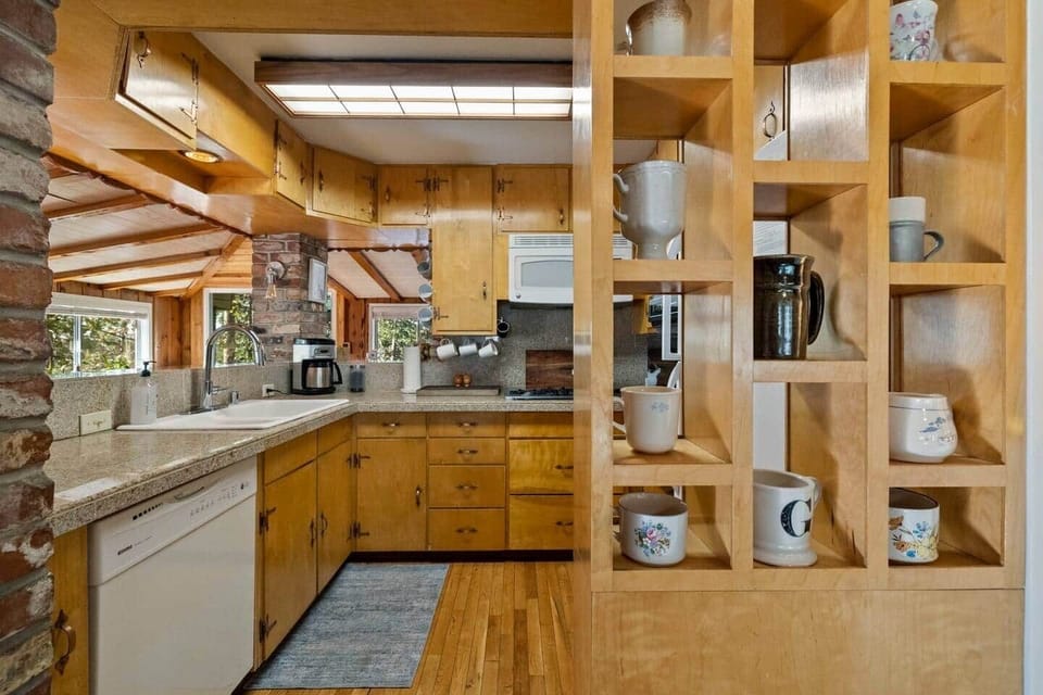 Fuel your mornings in style! This kitchen boasts a unique display of coffee mugs, a coffee pot, & Keurig, along with offering everything you need to cook up a storm and enjoy your favorite brew. #coffeelovershaven