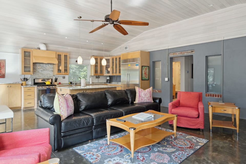 The open living room with multiple comfortable seating areas and queen size sleeper sofa and large TV.