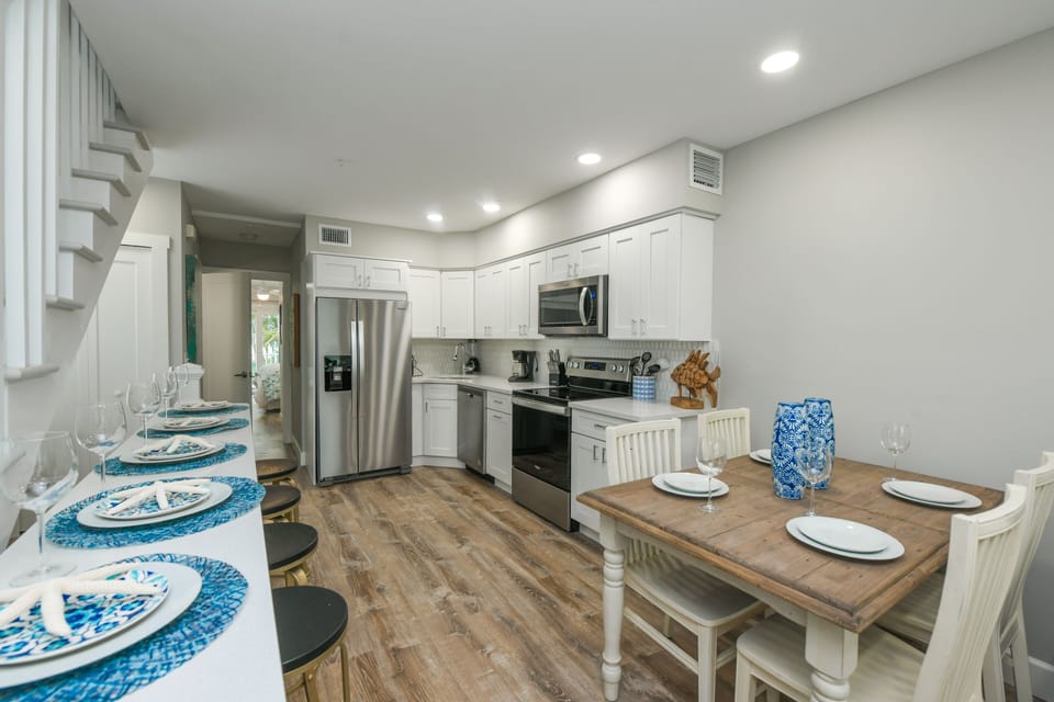 The fully equipped kitchen offers stainless steel appliances, ample prep space, and a dining table ready for shared meals.