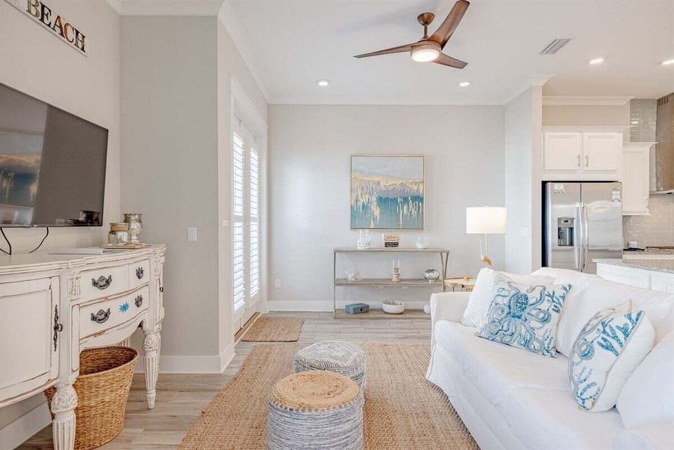 A stylish and comfortable sitting nook with natural lighting, plush seating, and tasteful beach-inspired artwork.