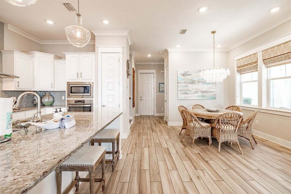 A beautifully decorated dining space with a beach-inspired painting, a chic chandelier, and a cozy atmosphere.
