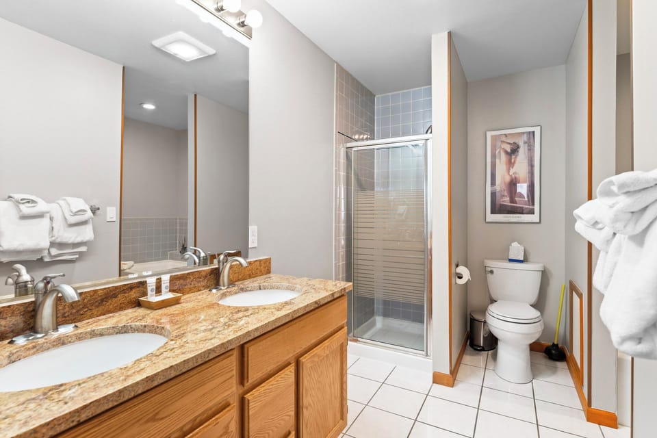 Refresh in your pristine bathroom featuring dual vanities, granite counters, glass shower, and plush towels for a spa-like experience.