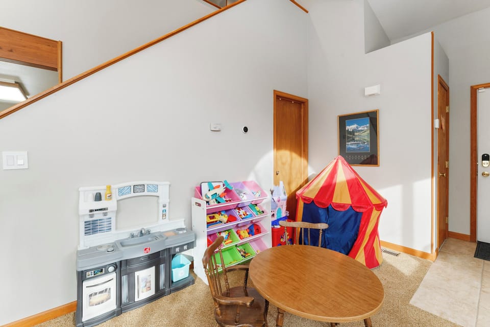 A magical play space awaits your little ones with a colorful circus tent, toy kitchen, and organized play shelves in this dedicated children's area.