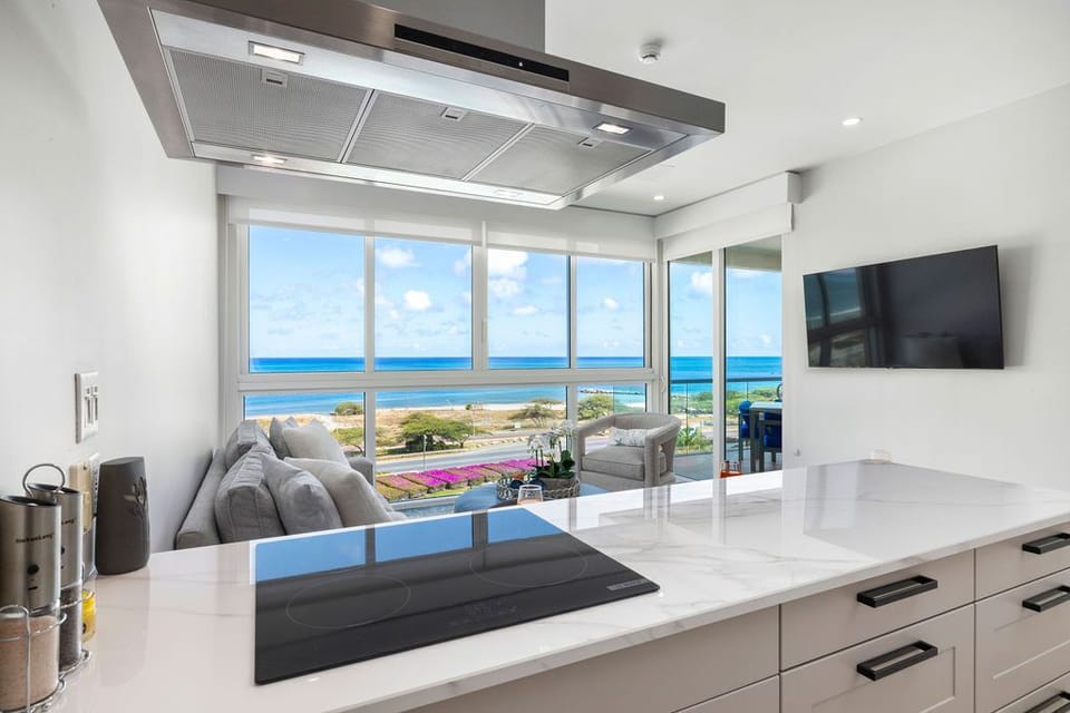 Your sleek, modern kitchen opens to stunning ocean views—perfect for preparing meals while gazing at the azure waters and coastal landscape beyond your windows.
