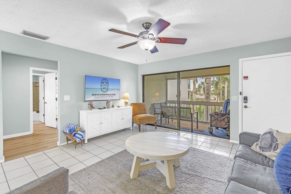 Living area spacious and sunny, opens to covered balcony with royal palm view.