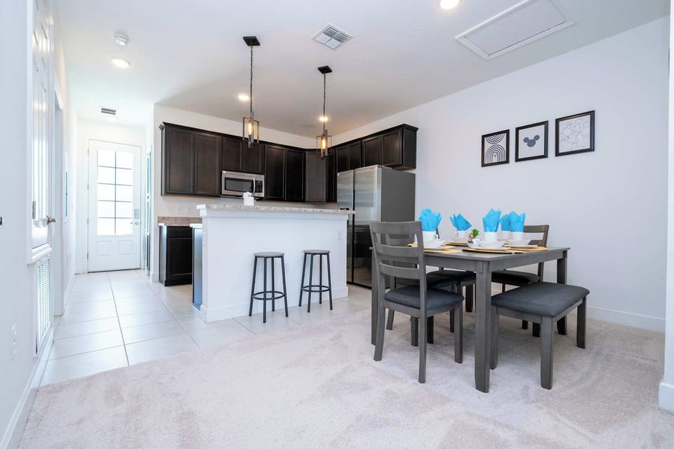 Bright open kitchen with dark shaker cabinets, stainless appliances, and pendant lights-gather at the breakfast bar or the 6-seat dining table for home-cooked meals.