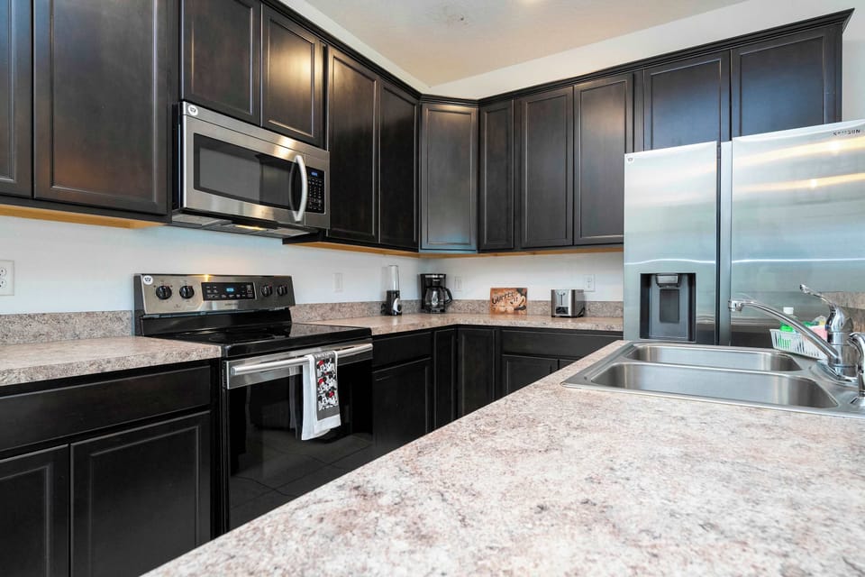 Fully equipped kitchen with dark shaker cabinets, stainless appliances, and long prep counters-perfect for cooking together and morning coffee.