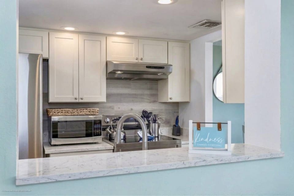 Granite & stainless kitchen with a large pass thru allowing for views of the ocean when cooking