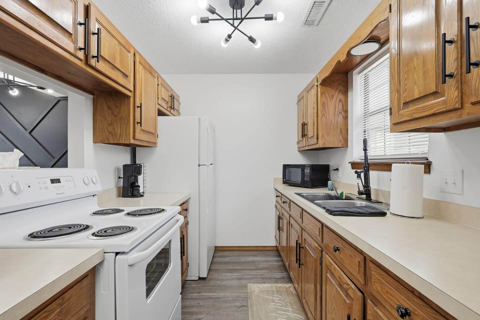 Full galley kitchen with electric range, microwave and full size fridge