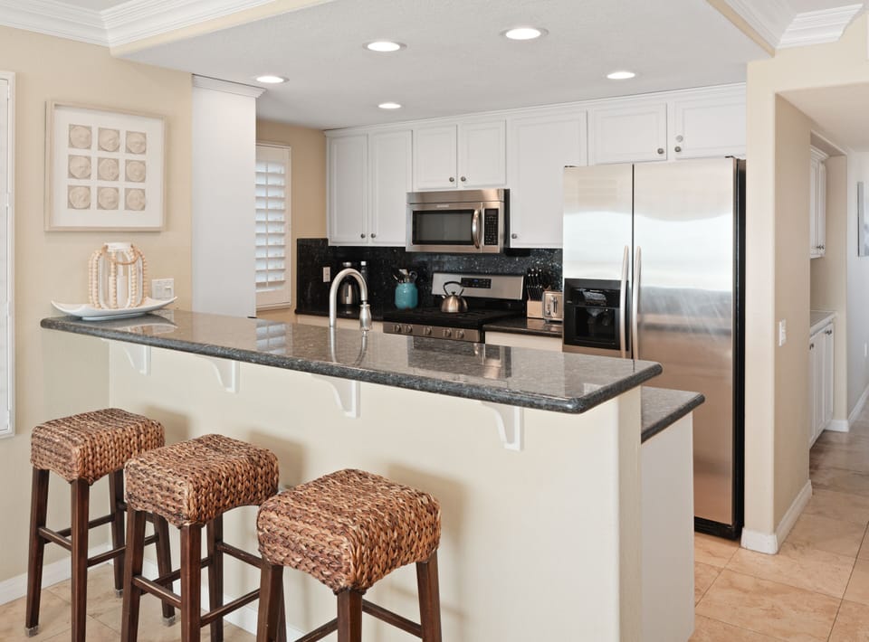 Modern Kktchen featuring high-end appliances, sleek countertops, and a stylish bar with stools for casual dining.