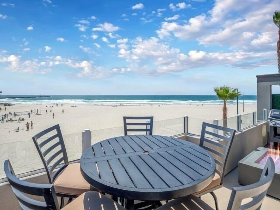 Spacious outdoor space with dining table, a grill, and panoramic sea views, perfect for alfresco meals.