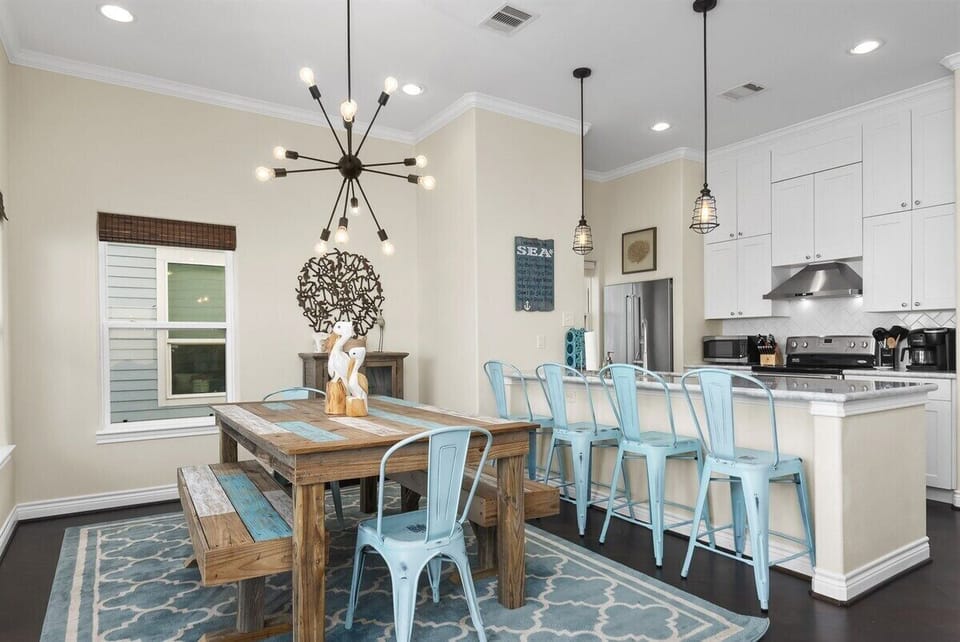 Fully equipped kitchen featuring stainless steel appliances, white cabinetry, pendant lighting, and bar seating for casual dining.