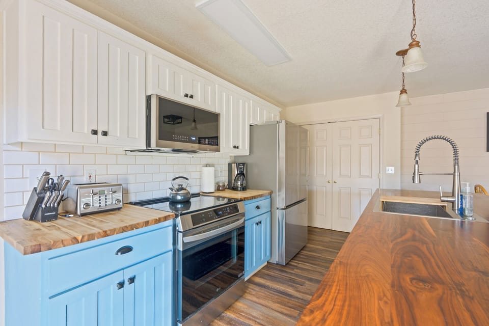 Your charming kitchen features butcher block counters, stainless appliances, and cheerful blue accents - perfect for preparing meals together.