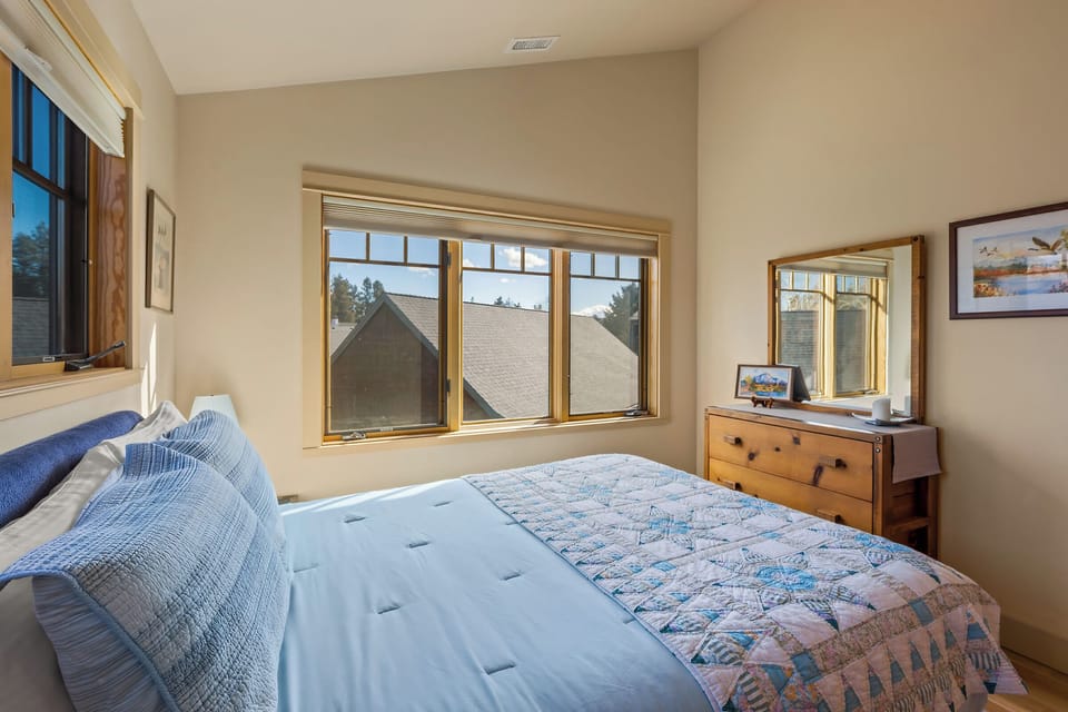 Settle into your cozy bedroom with soft blue linens and warm natural light streaming through windows.