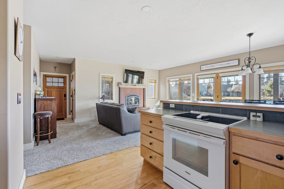 Your open-concept space seamlessly blends kitchen and living areas, with warm wood cabinetry and a cozy fireplace creating the perfect atmosphere for your stay.