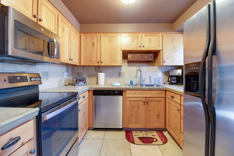 Your fully equipped kitchen features warm wood cabinetry and stainless steel appliances, with everything you need to prepare meals during your mountain getaway.
