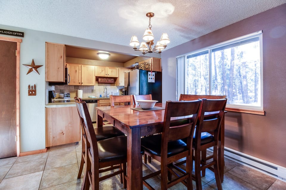 Gather around this inviting dining table with snowy forest views just beyond the window, perfect for cozy meals after a day of mountain adventure.