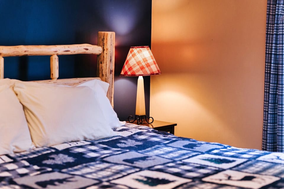 Close-up of plaid bedding and bedside lamp adds rustic warmth for a cozy cabin night