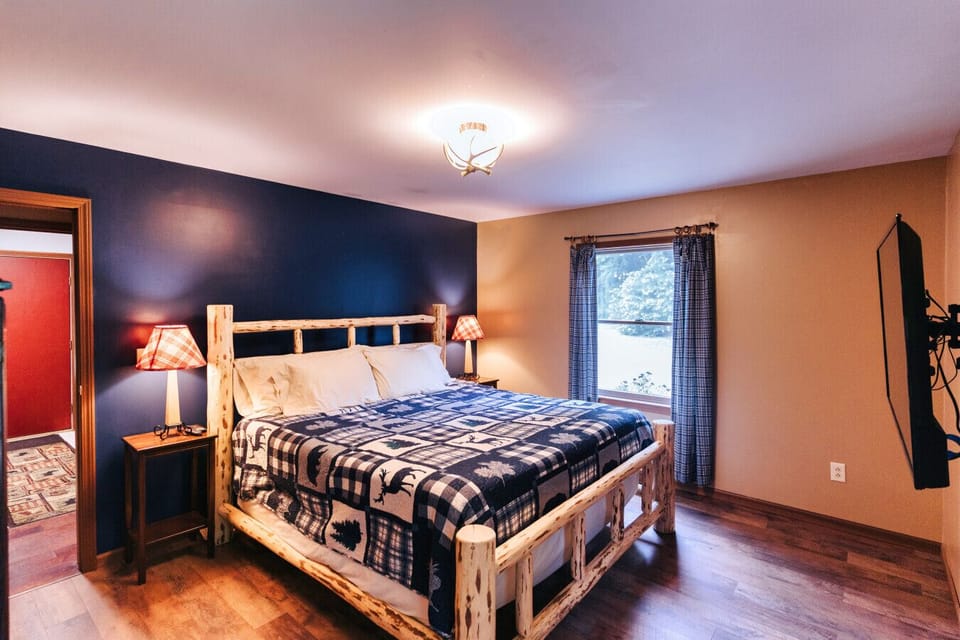 Log-frame bedroom with wall-mounted TV offers restful downtime after hiking, sightseeing, or family cabin days