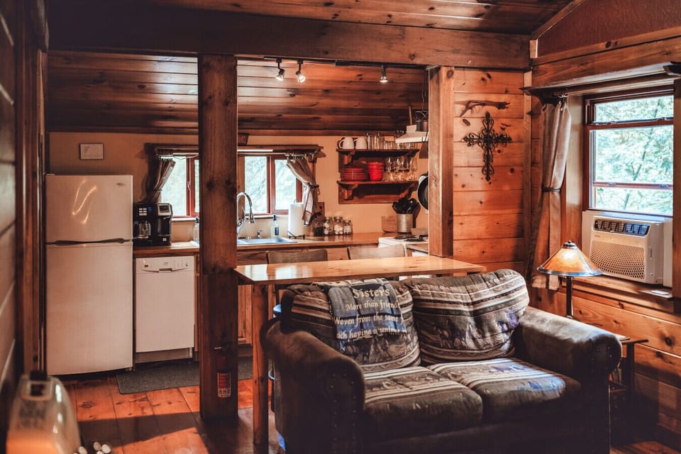 Compact living space with warm wood details and kitchen views makes the cozy cabin feel inviting