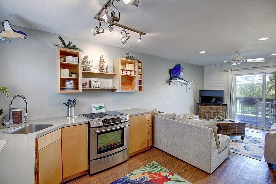 Your open-concept kitchen flows seamlessly into the living space, featuring modern appliances and coastal nautical decor that creates a welcoming atmosphere.