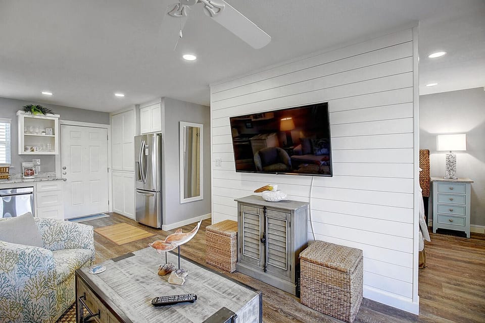 Unwind in your bright, open living space with coastal decor, modern kitchen, and shiplap accent wall for ultimate relaxation.