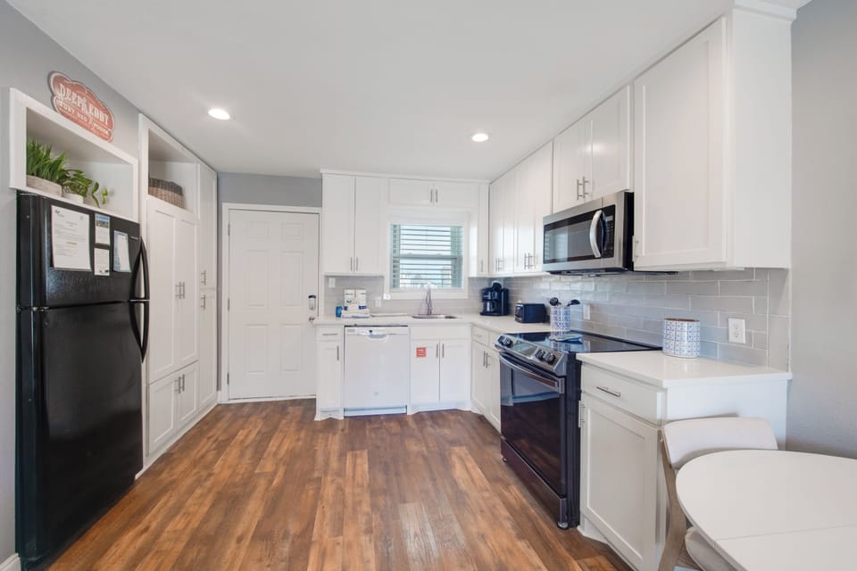 Step into your fully-equipped kitchen featuring crisp white cabinets, modern appliances, and warm wood floors—perfect for preparing memorable meals.