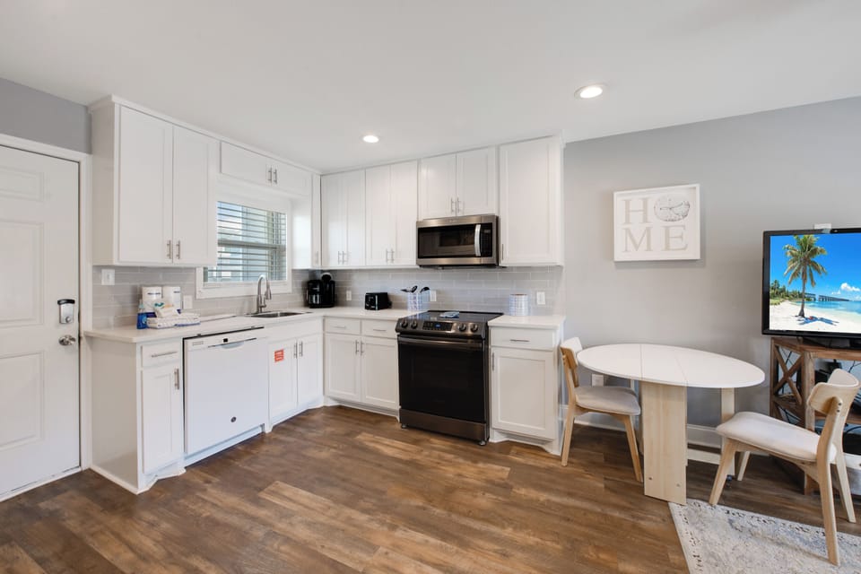 Your modern kitchen welcomes you with crisp white cabinets, stainless appliances, and cozy dining nook—perfect for morning coffee or family meals.