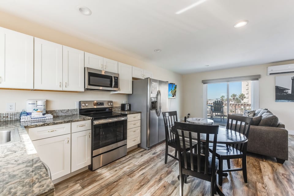 Your bright open-concept space features a fully equipped kitchen with granite counters and stainless appliances, flowing seamlessly into comfortable living and dining areas.