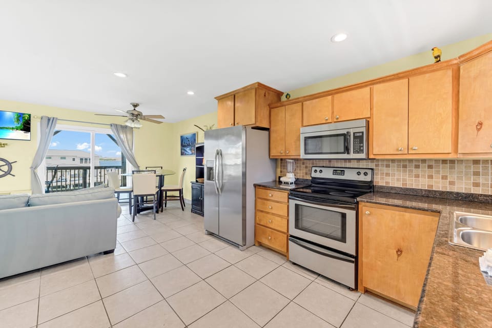 Your open-plan kitchen flows seamlessly into the living area, featuring granite counters, stainless appliances, and ocean views from every window.