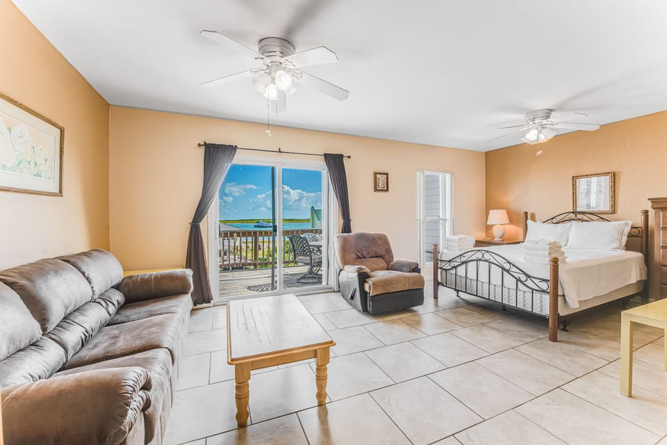 Relax in your spacious suite where comfort meets paradise - plush seating, a cozy bed, and stunning ocean views through your private balcony doors.