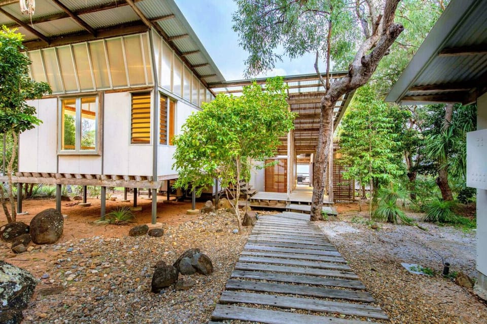 Elevated bushland home with stilts, wooden walkways, and modern styling, offering a private retreat within Sunrise at 1770.