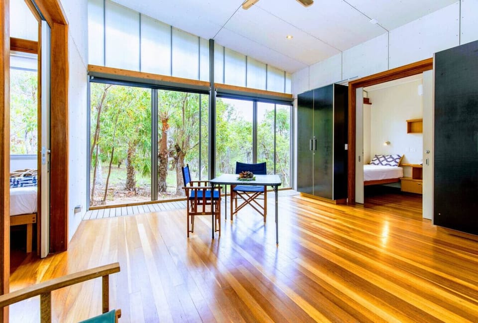 Living and dining area with timber flooring, large windows, and bushland outlook, connecting to bedrooms for convenience.