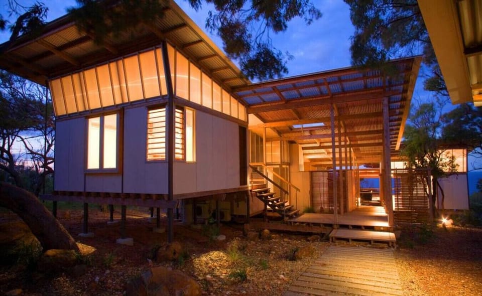 Elevated bushland home with stilts, glowing interiors, and modern styling, offering a private retreat within Sunrise at 1770.