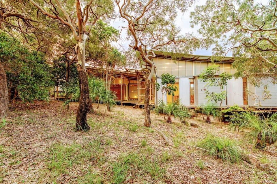 Elevated bushland home with glass panels and modern styling, offering a private retreat within Sunrise at 1770.