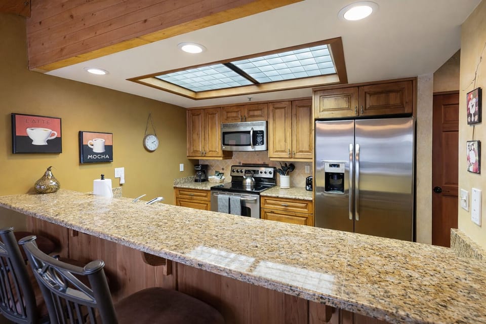 You'll love this spacious, fully equipped kitchen with warm wood cabinetry, granite countertops, stainless steel appliances, and a large breakfast bar perfect for casual dining and morning coffee.