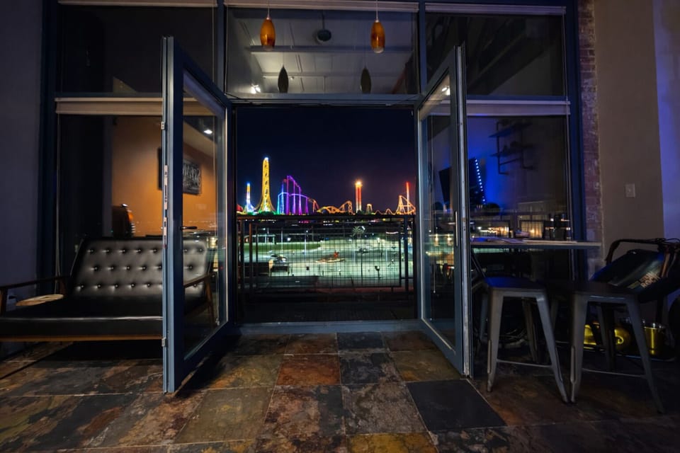 Nighttime condo views overlooking Lake Erie with Cedar Point glowing across the water. Open balcony doors frame the skyline, lights, and coaster views for a truly unforgettable stay.