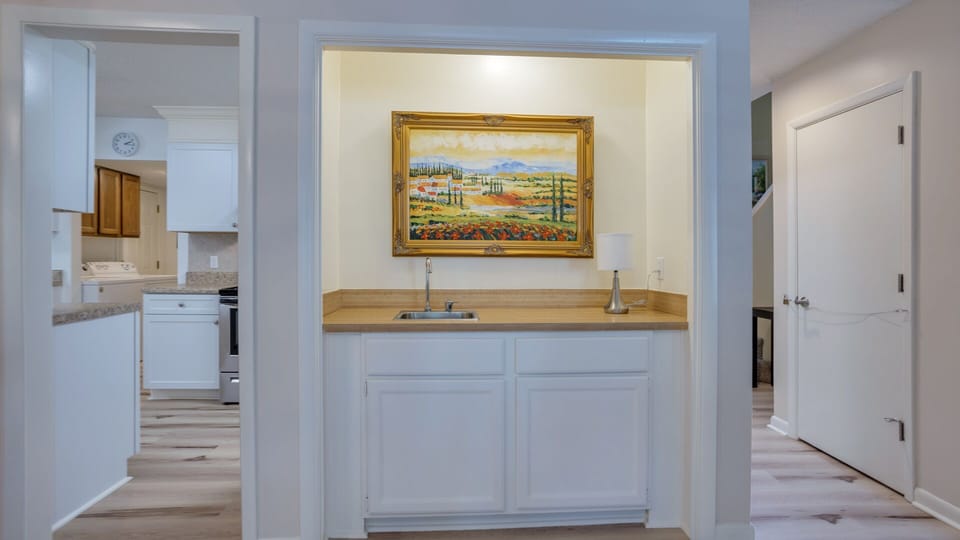 A built-in wet bar adds convenience, featuring cabinet storage, a sink, and dedicated counter space. Thoughtfully positioned between the kitchen and living area, it's ideal for entertaining.