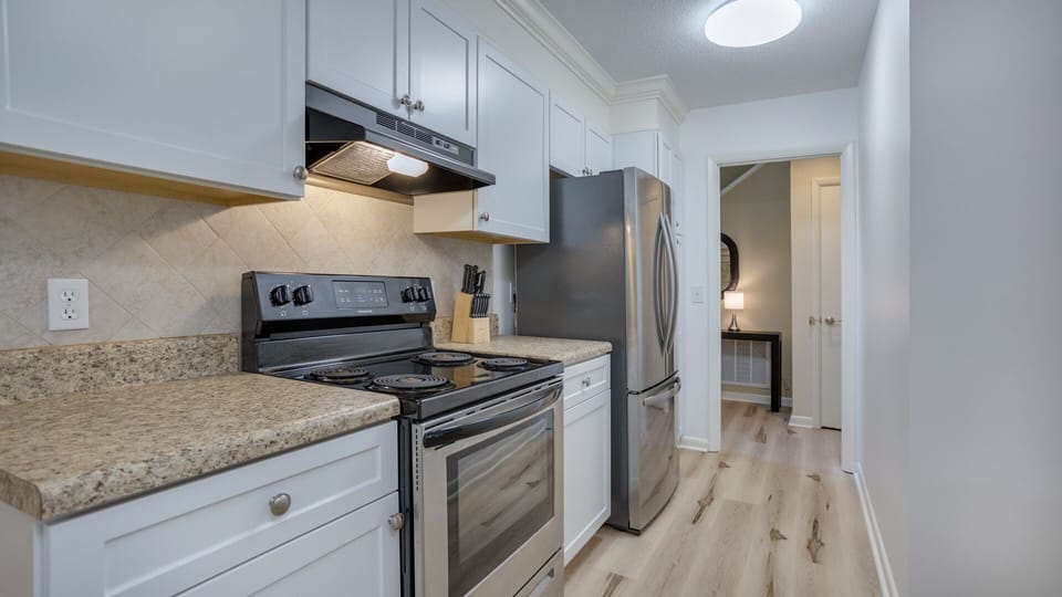 The kitchen features a clean, updated design with white cabinetry, granite countertops, and stainless steel appliances.