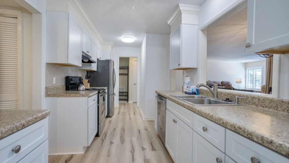 This galley-style kitchen offers an efficient layout with crisp white cabinetry, granite countertops, and stainless steel appliances.