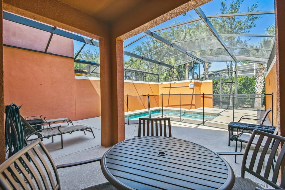 Step outside to your private pool area, where sun-soaked loungers await on a spacious deck surrounded by vibrant orange walls. Enjoy al fresco dining at the circular table, framed by a protective screen for comfort and relaxation.