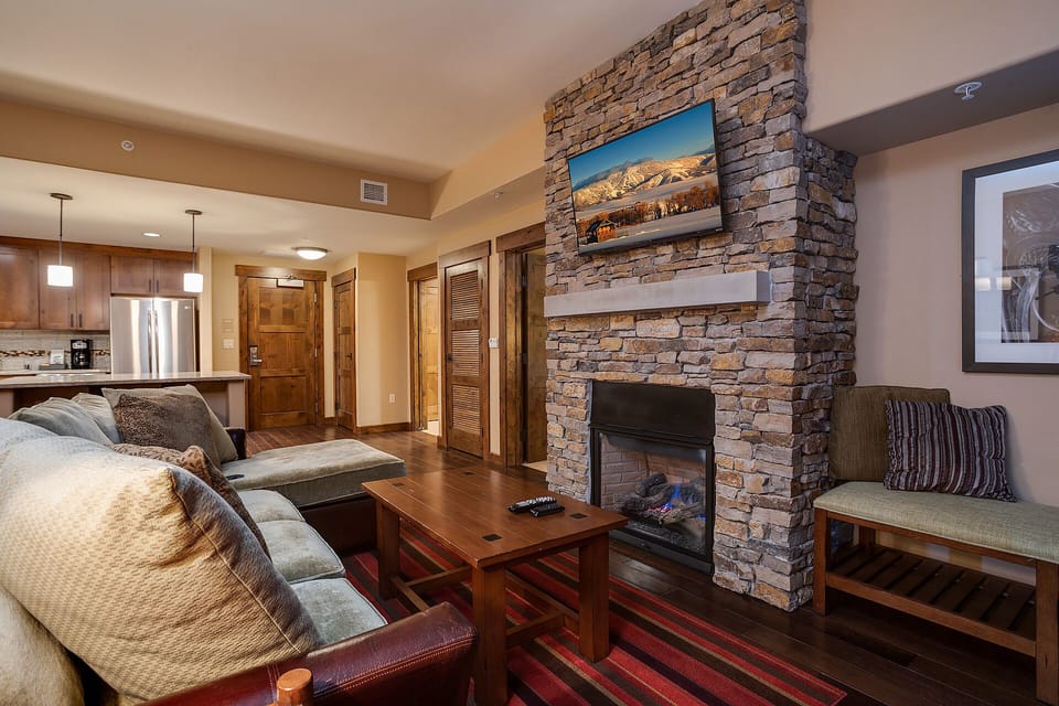 Unwind by your cozy stone fireplace with plush seating and mountain views on the wall-mounted TV.
