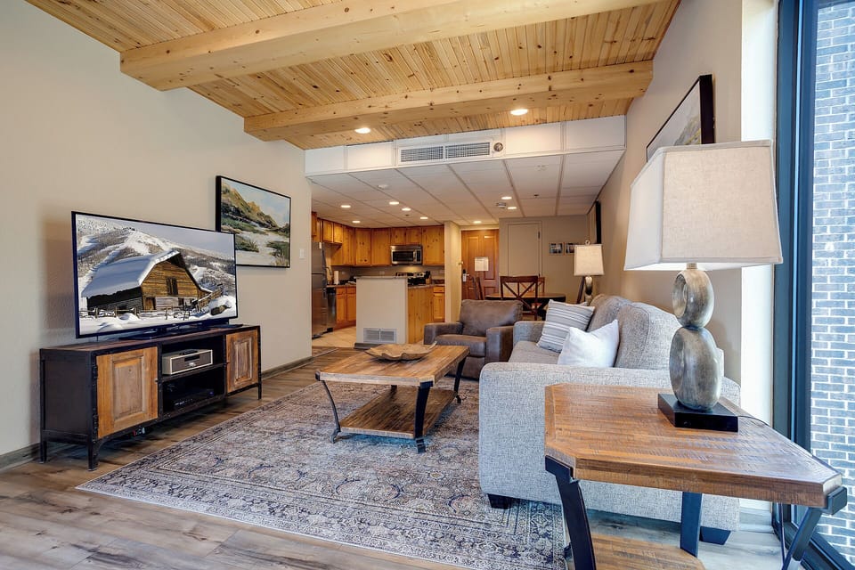Relax in your open-concept living space with soaring wood-beam ceilings, plush seating, and mountain artwork creating the perfect mountain getaway atmosphere.