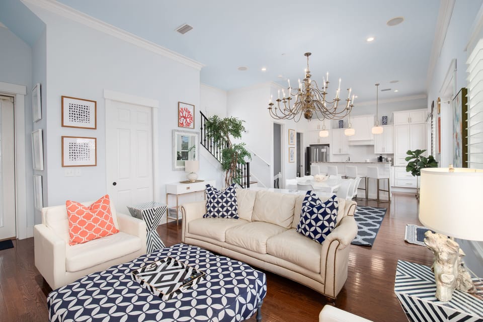 Relax in your bright, stylish living room with plush sofas, elegant chandelier, and open-concept flow to the modern kitchen.