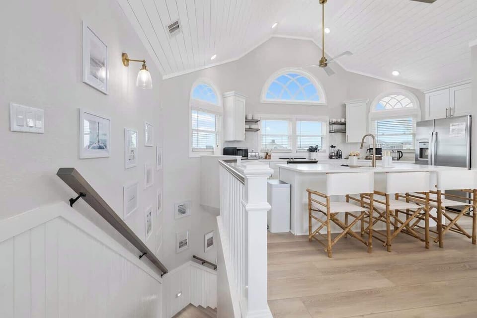 Nicely equipped kitchen with vaulted ceilings has refrigerator, stove, microwave dishwasher, blender, Keurig coffee maker, toaster, pots and pans, plates, glasses, wine glasses, coffee cups, cooking and eating utensils.